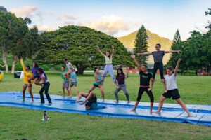 Young people from the church doing acrobatic poses on a lawn at Camp Waianae