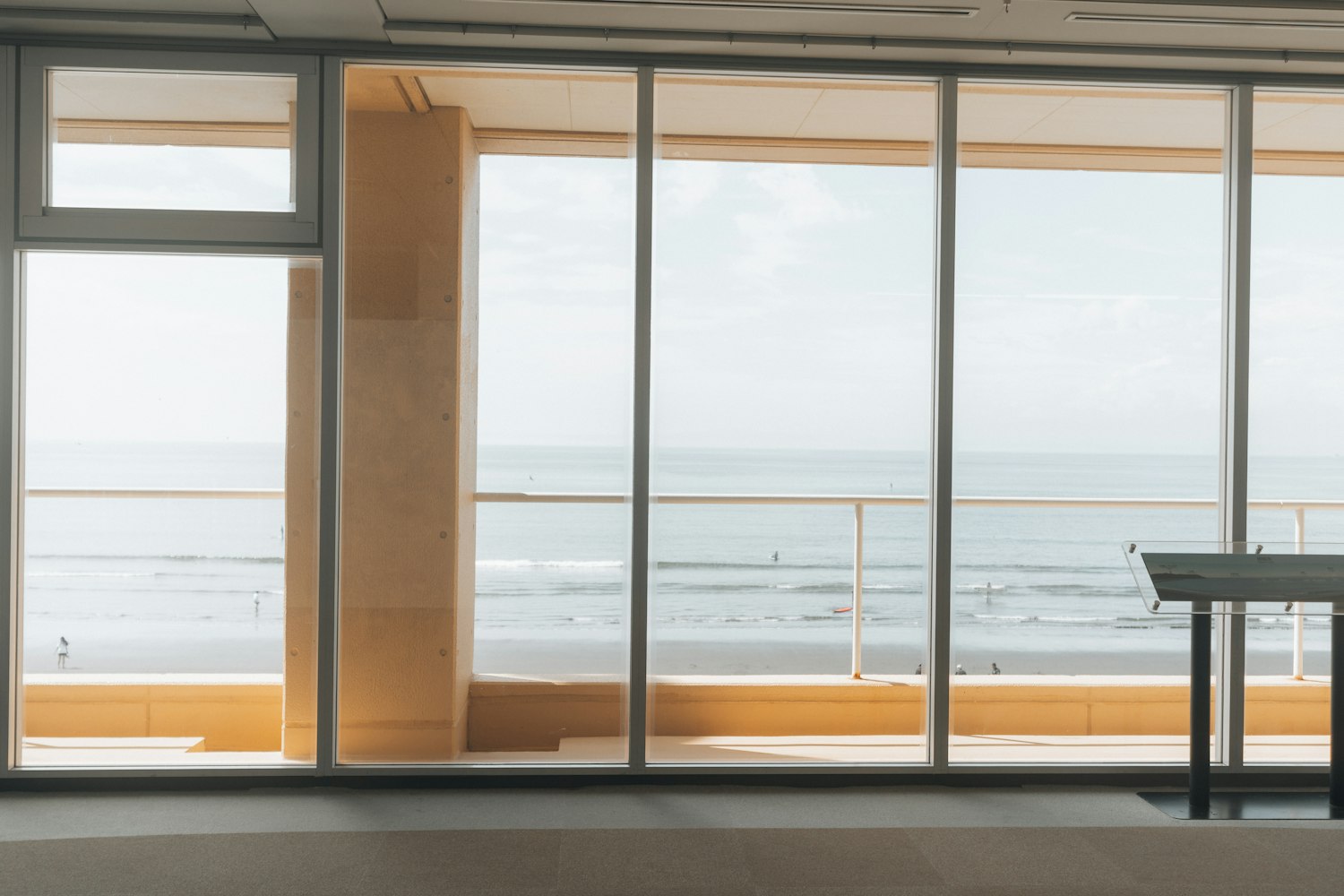The main room seen through full-height glazing, open water filling the view beyond.